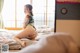 A woman in a bikini sitting on a bed.