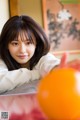 A woman laying on top of a table next to an orange.