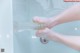 A person holding a bottle of water in a bathtub.