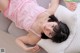 A woman laying on a couch in a pink dress.