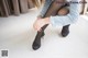 A woman in black stockings and high heels tying up her shoes.