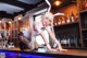 A woman in bunny ears sitting at a bar.