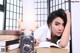 A woman sitting at a table with a camera and books.